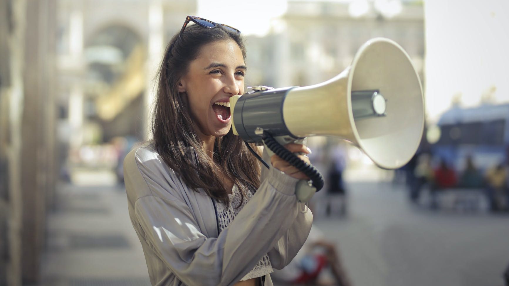 cheerful young woman screaming into megaphone